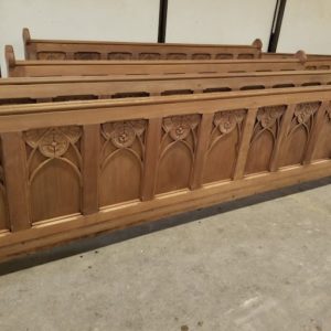 Unfinished wooden church pews with carved details