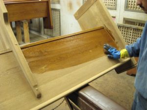 Applying stain to wooden church pew