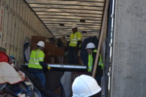 Workers unloading pews from a truck