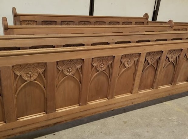 Unfinished wooden church pews with carved details