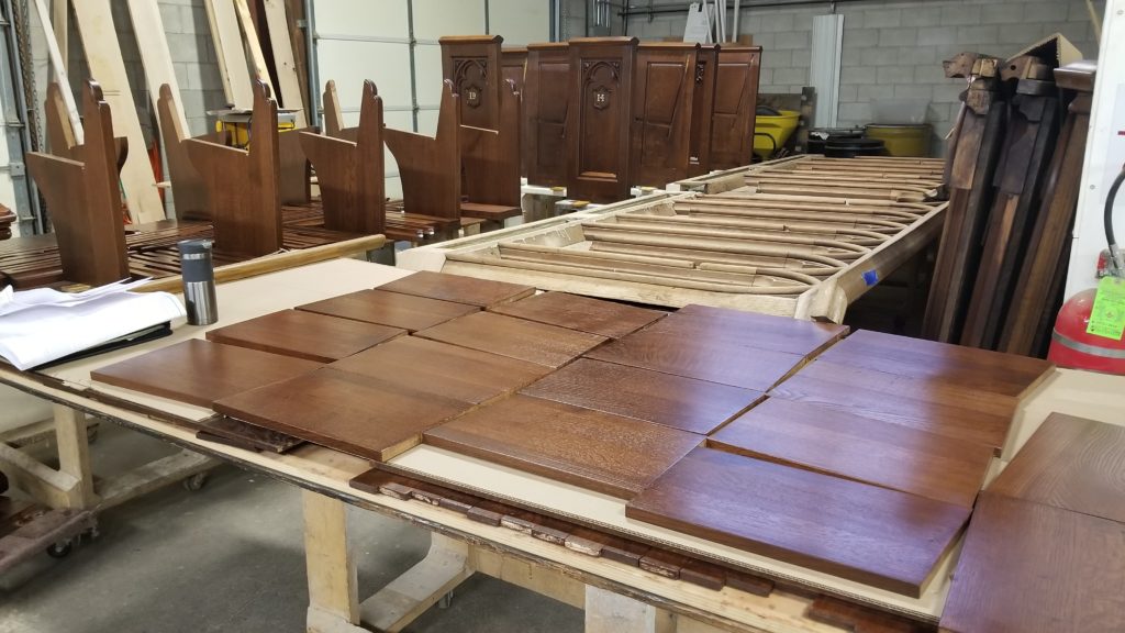 Unfinished wooden church pew pieces in the workshop waiting to be assembled